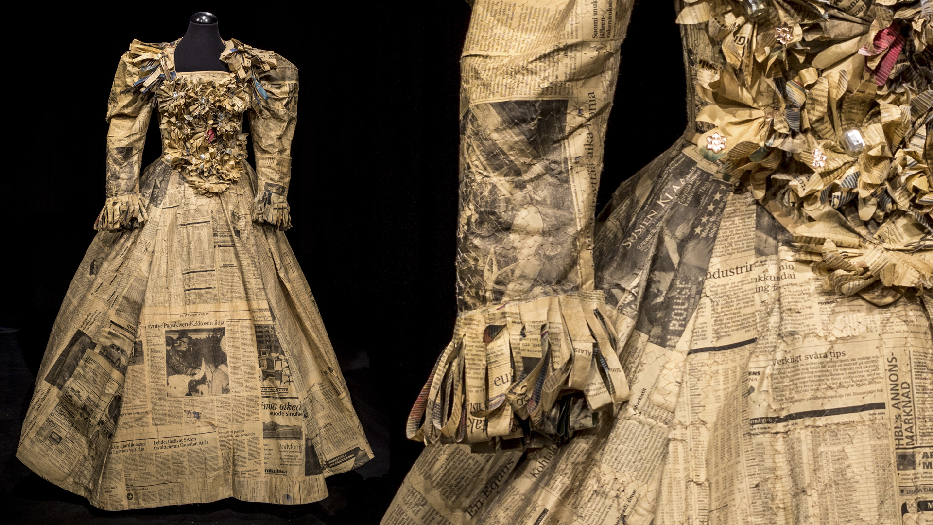Sanomalehtipaperista tehty naisen pitkä- ja leveähelmainen, pitkähihainen puku, jossa sanomalehtiruusukkeita etumuksessa ja rimpsuja hihansuissa. Lähikuvasta näkyy, miten puvun materiaali on valmistettu ompelemalla sanomalehtisivuja ompelukoneen sik-sak-ompeleella kankaaksi.
